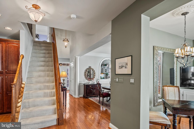 entrance foyer featuring a chandelier, baseboards, ornamental molding, stairway, and light wood-type flooring