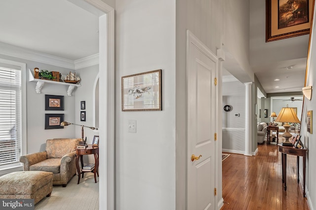 hallway featuring crown molding, hardwood / wood-style floors, and ornate columns