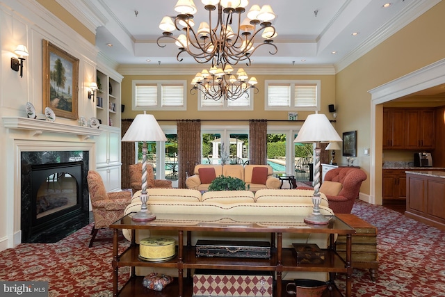 dining room featuring ornamental molding, a high end fireplace, a raised ceiling, and built in shelves