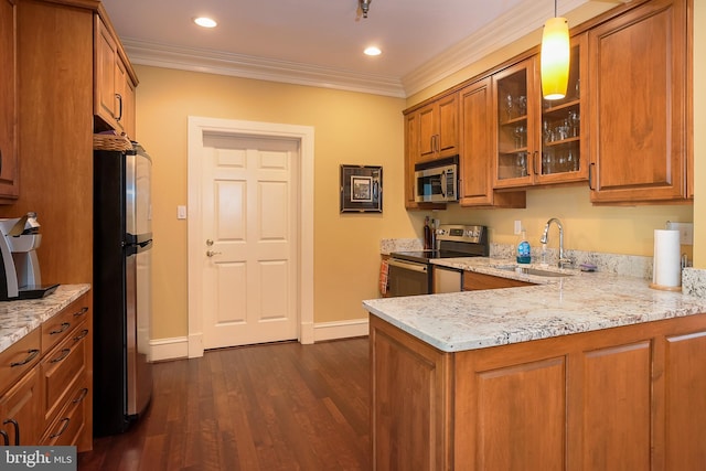 kitchen featuring brown cabinets, light stone countertops, stainless steel appliances, crown molding, and a sink