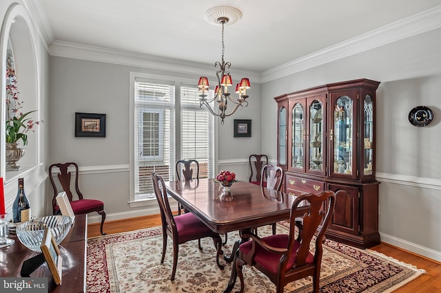 dining area featuring light wood-style flooring, baseboards, a notable chandelier, and ornamental molding