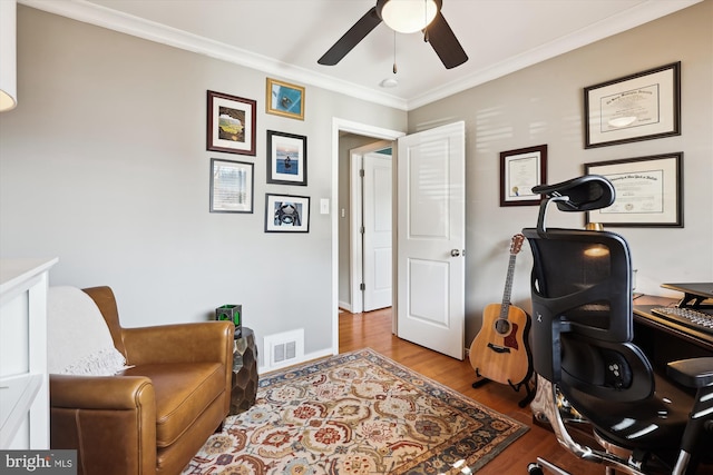 office space featuring baseboards, visible vents, a ceiling fan, light wood-style flooring, and ornamental molding