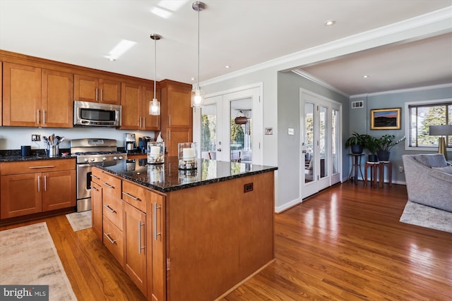 kitchen featuring dark stone counters, a kitchen island, stainless steel appliances, french doors, and pendant lighting