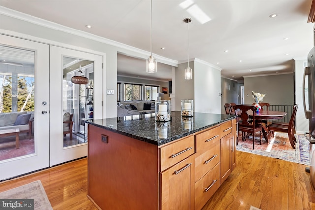 kitchen with a center island, french doors, decorative light fixtures, open floor plan, and dark stone counters