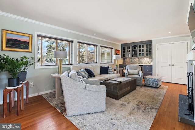 living room with baseboards, crown molding, and wood finished floors