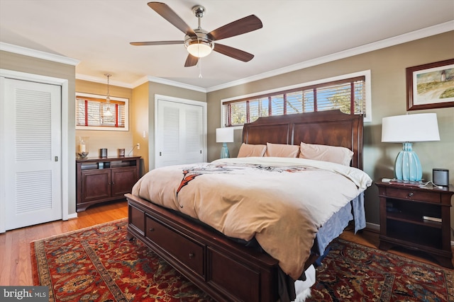 bedroom with multiple closets, crown molding, light wood finished floors, and ceiling fan