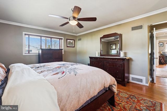 bedroom featuring light wood-type flooring, baseboards, visible vents, and ornamental molding