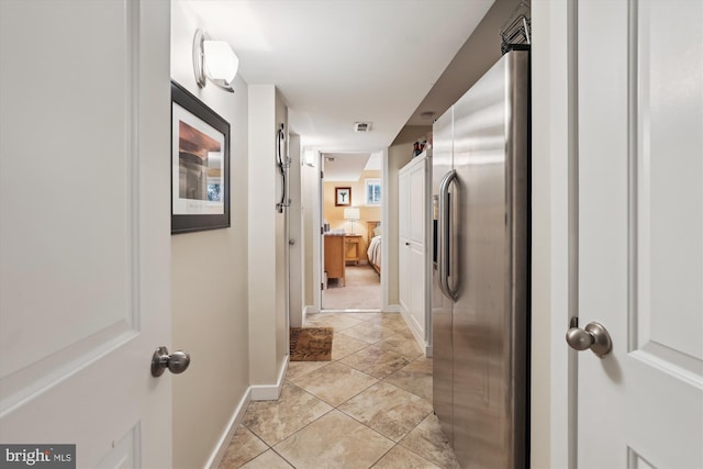 hallway with light tile patterned flooring, visible vents, and baseboards