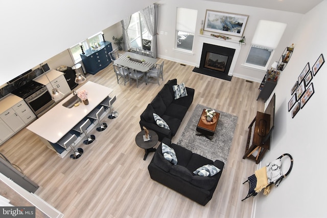 living area featuring a fireplace with flush hearth, visible vents, baseboards, and wood finished floors