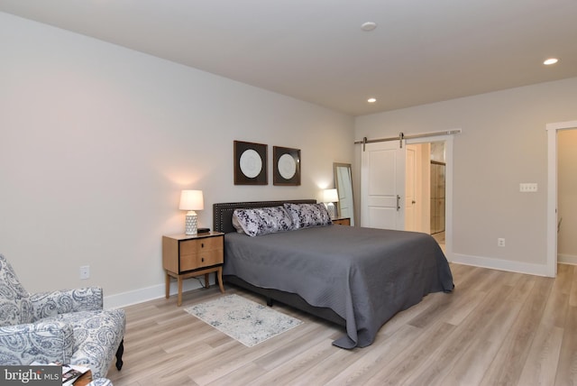 bedroom featuring light wood-type flooring, recessed lighting, baseboards, and a barn door