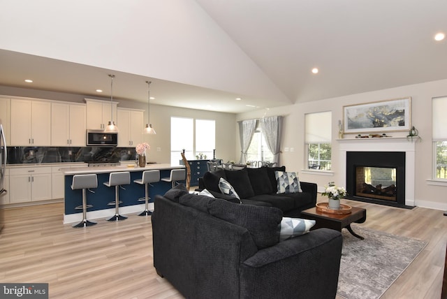 living room with recessed lighting, light wood-style floors, a multi sided fireplace, high vaulted ceiling, and baseboards