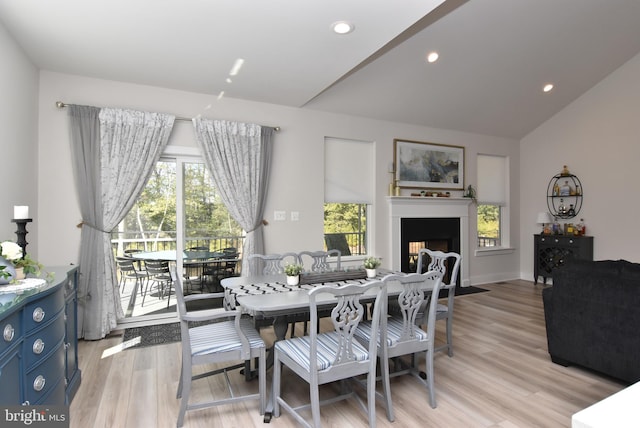 dining space featuring recessed lighting, light wood-style flooring, vaulted ceiling, and a fireplace with flush hearth