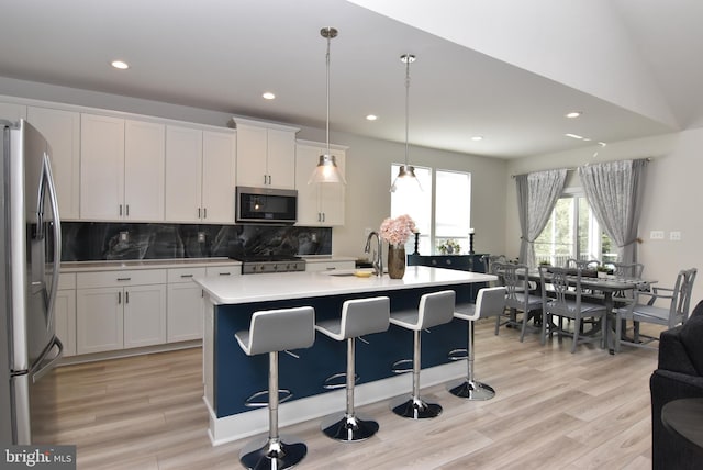 kitchen featuring stainless steel appliances, light countertops, decorative backsplash, white cabinetry, and a sink