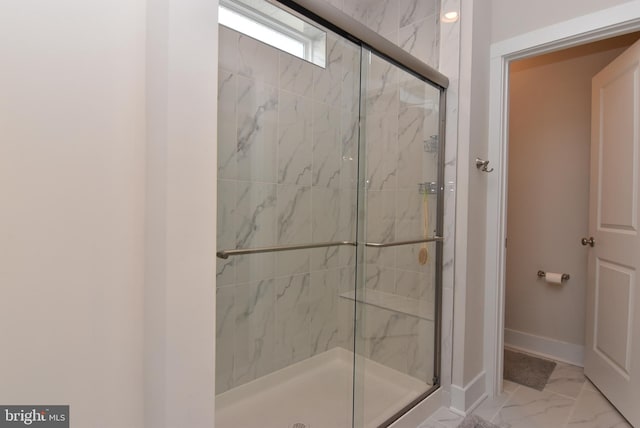 bathroom featuring marble finish floor, a marble finish shower, and baseboards