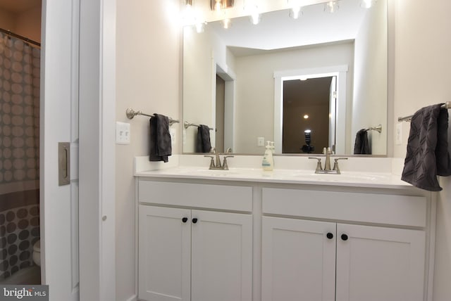 bathroom with a shower with shower curtain, a sink, toilet, and double vanity