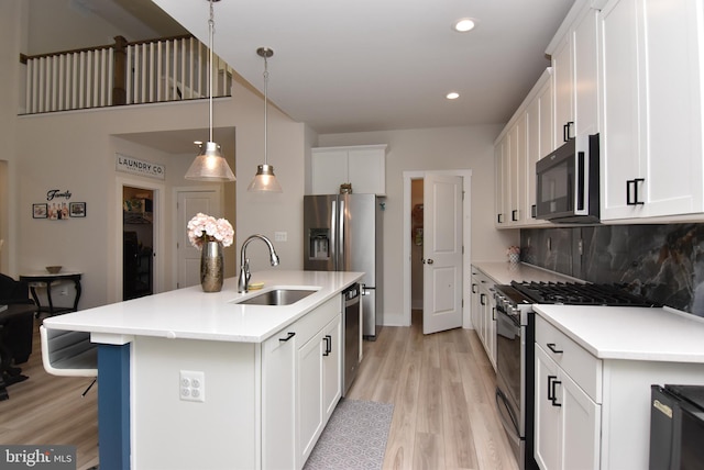 kitchen featuring white cabinets, appliances with stainless steel finishes, decorative backsplash, and a sink