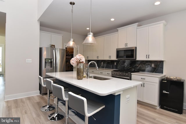 kitchen with tasteful backsplash, white cabinets, light wood-style flooring, stainless steel appliances, and a sink