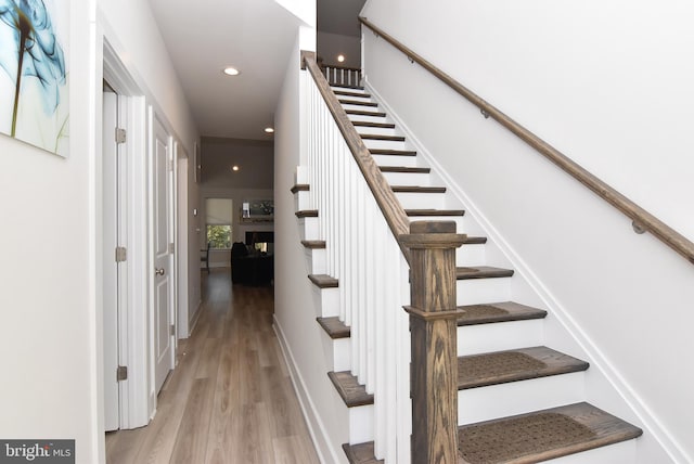 stairs featuring wood finished floors and recessed lighting