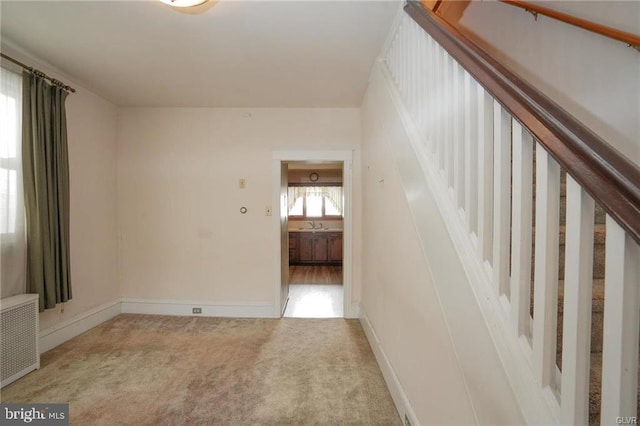 empty room with light carpet, baseboards, and radiator