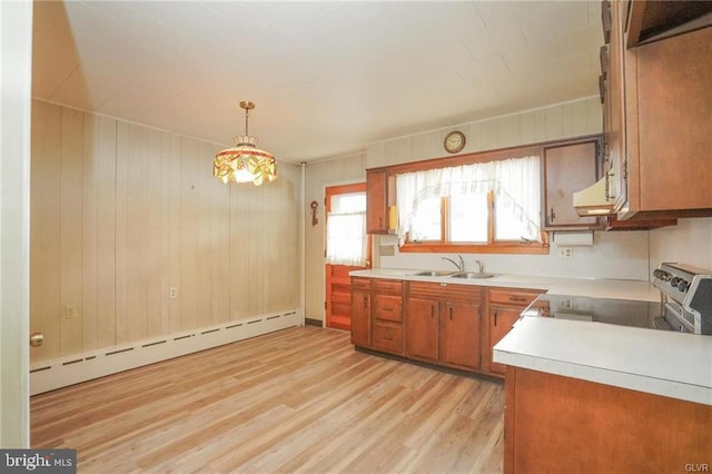 kitchen featuring a sink, light countertops, baseboard heating, brown cabinetry, and pendant lighting