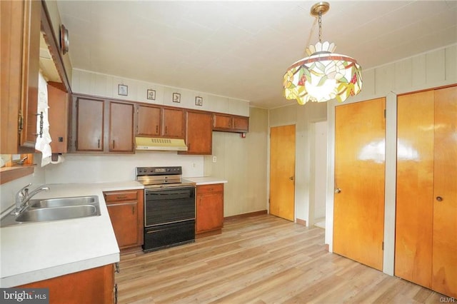 kitchen featuring under cabinet range hood, range with electric cooktop, light countertops, and a sink