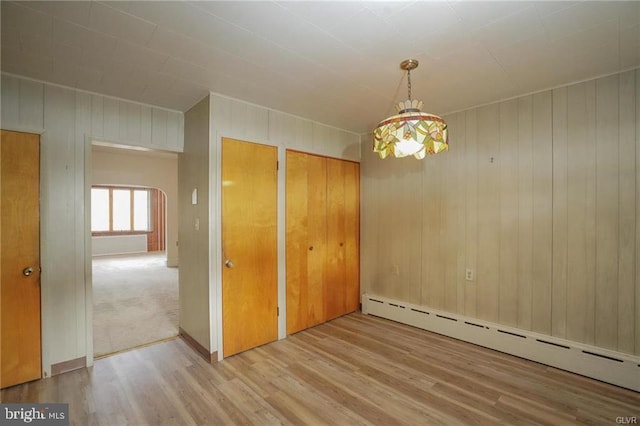 unfurnished room with a baseboard radiator and wood finished floors