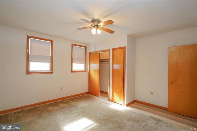 unfurnished bedroom with ceiling fan, light carpet, two closets, and baseboards