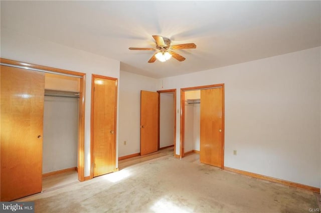 unfurnished bedroom with baseboards, two closets, and light colored carpet