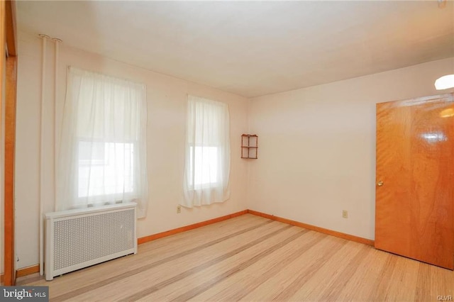 spare room with light wood-style floors, radiator, and baseboards