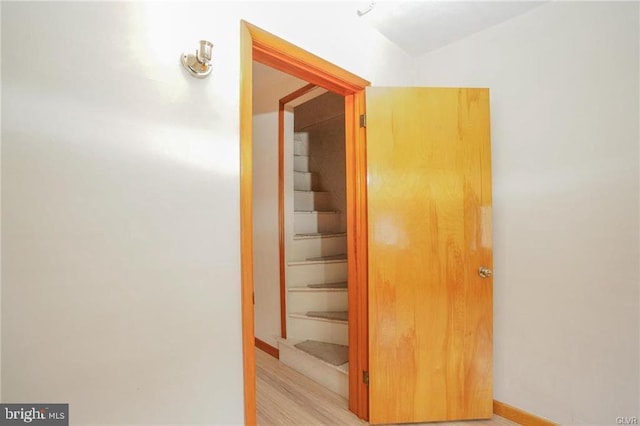 hallway with stairway, light wood-type flooring, and baseboards