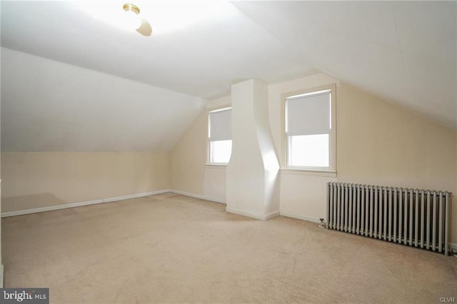 bonus room featuring light carpet, radiator heating unit, vaulted ceiling, and baseboards