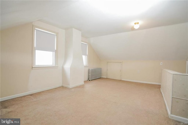 bonus room with lofted ceiling, baseboards, light carpet, and radiator heating unit