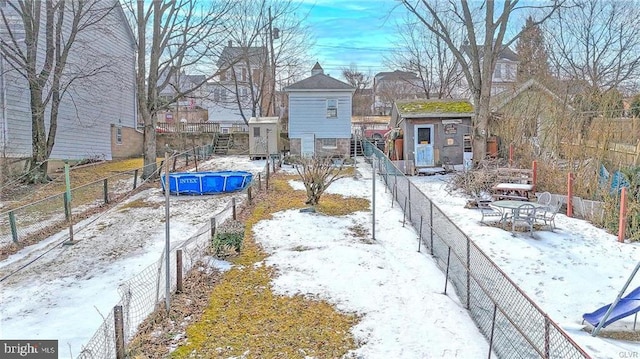 yard covered in snow with a shed, an outdoor structure, and fence