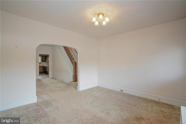 unfurnished room with baseboards, stairs, arched walkways, and light colored carpet