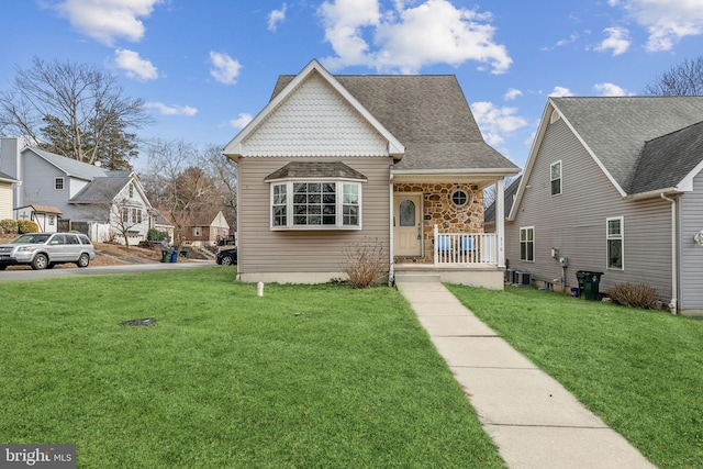 view of front of house featuring a porch, stone siding, a front lawn, and central air condition unit