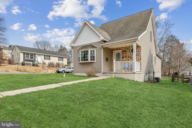 view of front of home featuring covered porch, stone siding, central AC, and a front yard