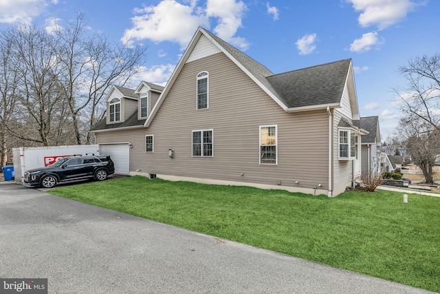 view of side of property with a garage, a yard, and a shingled roof