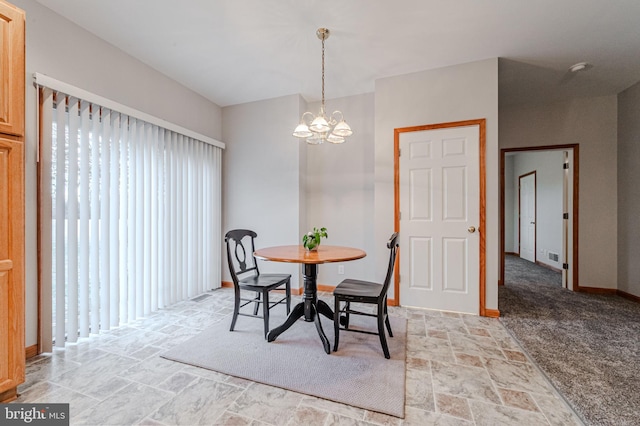 dining space with a chandelier, stone finish flooring, plenty of natural light, and baseboards