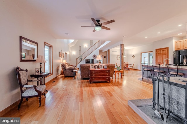 living room featuring recessed lighting, a ceiling fan, baseboards, stairs, and light wood-style floors