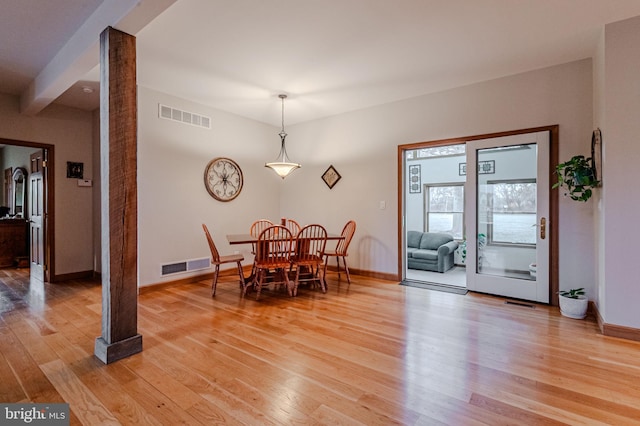 dining room featuring baseboards, light wood-style floors, visible vents, and ornate columns