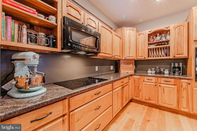 kitchen featuring dark stone countertops, light wood-style flooring, black appliances, and open shelves