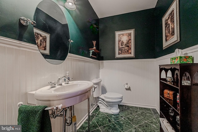 bathroom with a wainscoted wall, tile patterned flooring, and toilet