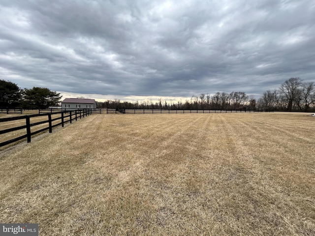 view of yard featuring an enclosed area, a rural view, fence, and an outdoor structure