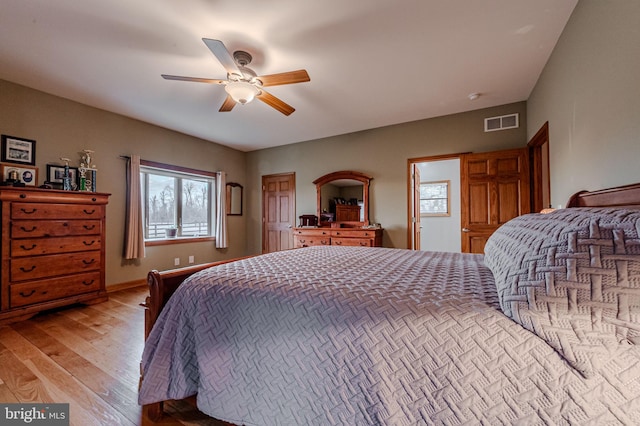 bedroom featuring a ceiling fan, visible vents, light wood-style flooring, and baseboards