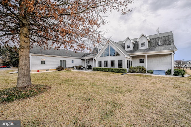 back of property with a shingled roof, a lawn, and a patio area