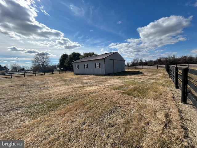 view of yard featuring an outbuilding, a rural view, and fence