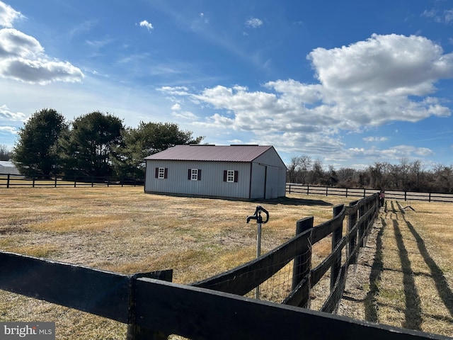 view of yard with an outbuilding, a rural view, an outdoor structure, and fence