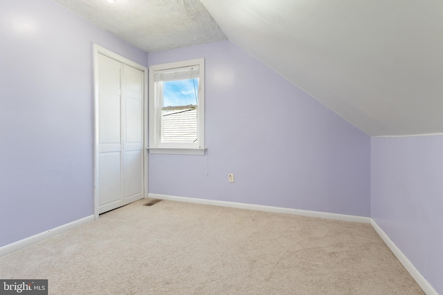 additional living space featuring light carpet, visible vents, baseboards, and lofted ceiling