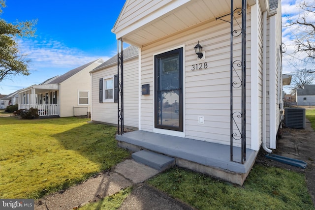 entrance to property with a porch, central AC, and a yard