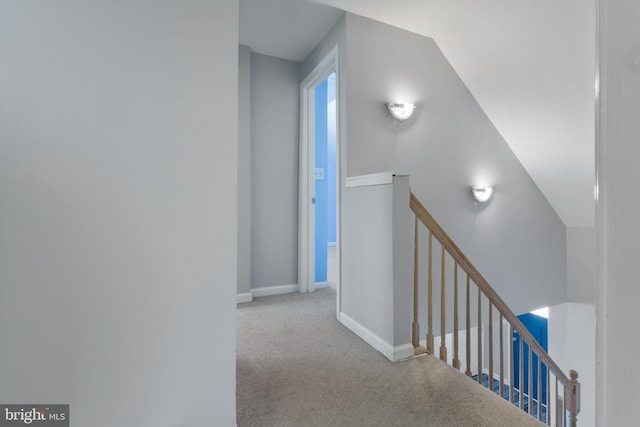 hallway featuring baseboards, light colored carpet, and an upstairs landing